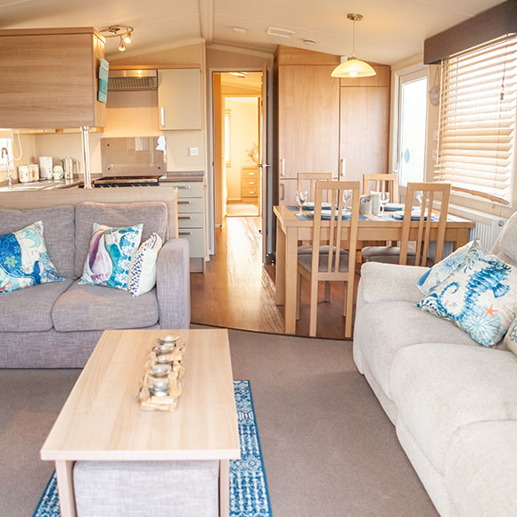 the inside of The Salty Air Retreat's caravan, showcasing the kitchenette, dining area and lounge 